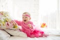 Portrait of a cute little baby girl with a princess crown on the head, in pink dress laughing and lying on the bed Royalty Free Stock Photo