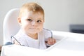 Portrait of cute little baby girl sitting in high chair and waiting for feeding Royalty Free Stock Photo