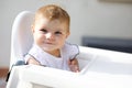 Portrait of cute little baby girl sitting in high chair and waiting for feeding Royalty Free Stock Photo