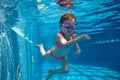 Portrait of cute little baby girl, toddler in pink swimsuit and goggles diving, swimming underwater in swimming pool Royalty Free Stock Photo