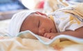 The portrait of cute little baby infant  boy wearing white hat lay to sleep prone on the bed, a yellow blanket in his room Royalty Free Stock Photo