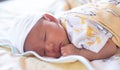 The portrait of cute little baby infant  boy wearing white hat lay to sleep prone on the bed, a yellow blanket in his room Royalty Free Stock Photo