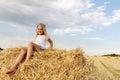 Portrait of cute little blond beautiful adorable cheerful caucasian kid girl enjoy sitting on hay stack or bale on Royalty Free Stock Photo