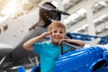 Portrait of cute little blond happy kid boy enjoy have fun play riding pedat toz plane model against vintage airplane