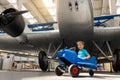 Portrait of cute little blond happy kid boy enjoy have fun play riding pedat toz plane model against vintage airplane