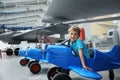 Portrait of cute little blond happy kid boy enjoy have fun play riding pedat toz plane model against vintage airplane