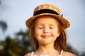 Portrait of cute little blonde girl in straw hat with closed eyes outdoor. Face closeup, smiley face, true happiness Royalty Free Stock Photo