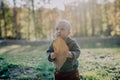 Portrait of cute little boy with big leaf wearing knitted hoodie in nautre, autumn concept. Royalty Free Stock Photo