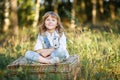 A portrait of a cute little boy with blue eyes and long blond hair sitting on a basket outside at sunset Royalty Free Stock Photo