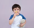 Portrait of cute little boy eating lollipop and hugging teddy bear, Adorable kid with smiling face holding sweets candy and Royalty Free Stock Photo