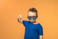 Portrait of a cute little boy giving thumbs down sign with sad expression on orange background. Royalty Free Stock Photo