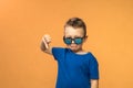 Portrait of a cute little boy giving thumbs down sign with sad expression on orange background. Royalty Free Stock Photo