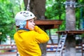 Portrait of cute  little boy in a helmet on a carbine crosses the rope in an extreme rope park  on summer vacation Royalty Free Stock Photo