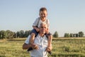 Portrait of cute little boy  and her handsome grandpa looking at camera and smiling on meadow. kid is sitting pickaback Royalty Free Stock Photo