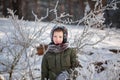 Portrait of a cute little boy in warm clothes playing outdoors during snowfall in winter sunny day Royalty Free Stock Photo