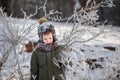 Portrait of a cute little boy in warm clothes playing outdoors during snowfall in winter sunny day Royalty Free Stock Photo