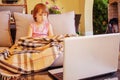 Portrait of cute little child girl sitting on the couch and trying to learn with laptop remotely Royalty Free Stock Photo