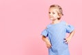 Portrait of cute little child girl wears blue dress while posing on pink studio background Royalty Free Stock Photo