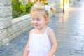 Portrait of cute little emotional blondy toddler girl in dress with soap bubbles breaking of her nose. Walk in the city park. Acti