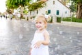 Portrait of cute little emotional blondy toddler girl in white dress playing and catching soap bubbles during walk in the city par Royalty Free Stock Photo