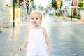 Portrait of cute little emotional blondy toddler girl in white dress playing and catching soap bubbles during walk in the city par Royalty Free Stock Photo