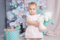 Portrait of a cute little european blond princess girl with a crown in a beautiful dress opening gifts in a studio decorated in Royalty Free Stock Photo