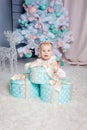 Portrait of a cute little european blond princess girl with a crown in a beautiful dress opening gifts in a studio decorated in Royalty Free Stock Photo