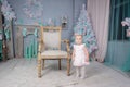 Portrait of a cute little european blond princess girl with a crown in a beautiful dress sitting on a vintage chair in a studio Royalty Free Stock Photo