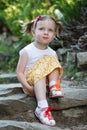 Portrait of a cute little girl on the background of nature. She`s sitting on the rocks Royalty Free Stock Photo