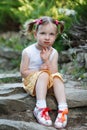 Portrait of a cute little girl on the background of nature. She`s sitting on the rocks Royalty Free Stock Photo