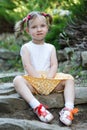 Portrait of a cute little girl on the background of nature. She`s sitting on the rocks Royalty Free Stock Photo