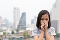 Portrait of cute little girl blowing nose in paper handkerchief,Asian child sneezing in a tissue in the city building as Royalty Free Stock Photo