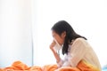 Portrait of cute little girl blowing nose in paper handkerchief,Asian girl sneezing in a tissue on bed