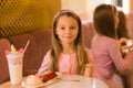 Portrait of a cute little girl in a cafe. Girl eats cake and cocktail with a unicorn Royalty Free Stock Photo