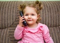 Portrait of a cute little girl on chair talking on the phone Royalty Free Stock Photo