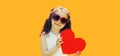 Portrait of cute little girl child with big red paper heart wearing heart shaped sunglasses on orange background Royalty Free Stock Photo