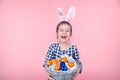 Portrait of a cute little girl with an Easter egg basket on an isolated pink background Royalty Free Stock Photo