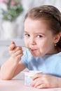 Portrait of cute little girl eating delicious yogurt Royalty Free Stock Photo