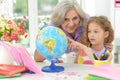 cute little girl with granddaughter at home looking at globe