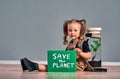 Portrait of cute little girl holding SAVE THE PLANET sign and looking at camera while protesting for nature, copy space