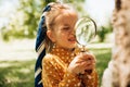 Portrait of cute little girl learning and exploring the nature with magnifying glass outdoors. Child playing with magnifying glass Royalty Free Stock Photo