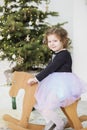 Portrait of a cute little girl. Little girl among Christmas decorations. Girl riding a rocking deer Royalty Free Stock Photo