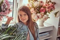 Portrait of a cute little girl with long brown hair and piercing glance wearing a stylish dress, posing with flowers Royalty Free Stock Photo