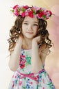 Portrait of cute little girl in nice spring dress, with flower wreath on head, showing emotions.