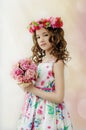 Portrait of cute little girl in nice spring dress, with flowery wreath on head, holds bouquet of flowers. Royalty Free Stock Photo