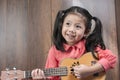 Cute Little Asian Girl playing ukulele. Royalty Free Stock Photo