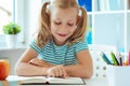 Portrait of a cute little girl read book at the table in classroom Royalty Free Stock Photo