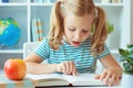 Portrait of a cute little girl read book at the table in classroom Royalty Free Stock Photo