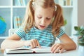 Portrait of a cute little girl read book at the table in classroom Royalty Free Stock Photo