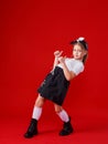 Portrait of a cute little girl in a white T-shirt and black skirt on a red background. Royalty Free Stock Photo